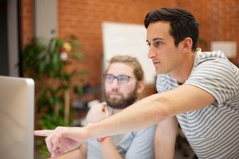 Two statistical analysts look at information on a desktop.
