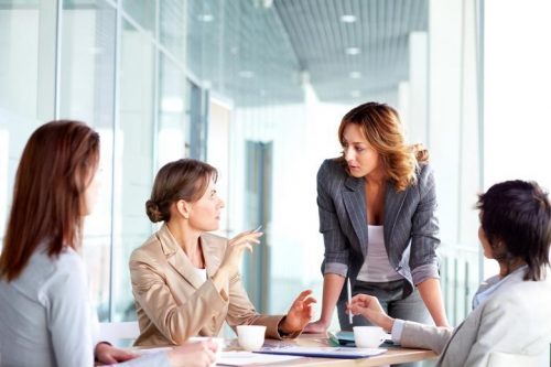 A business leader speaks with a team at a meeting.