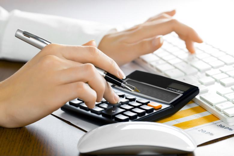 A finance professional uses a calculator and PC