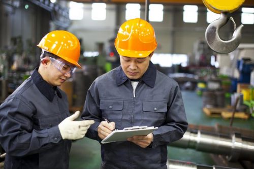 Factory workers writing a business reengineering report.