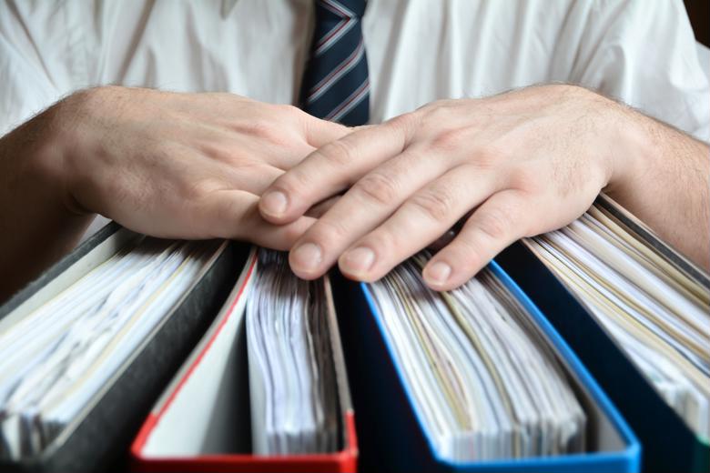 A tax accountant poses with binders of financial statements.