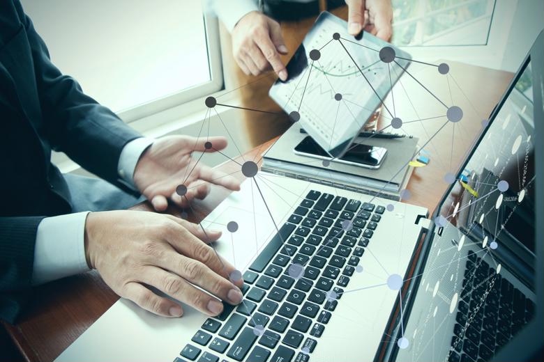 A manager uses a laptop while graphics represent data points.