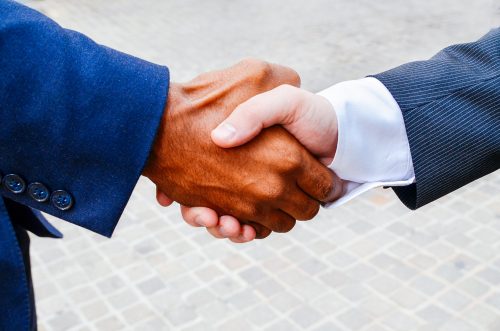 Two people in business suits shake hands.