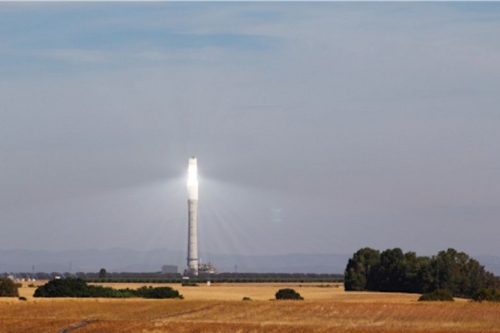 A tall tower in the countryside with a bright light at the top