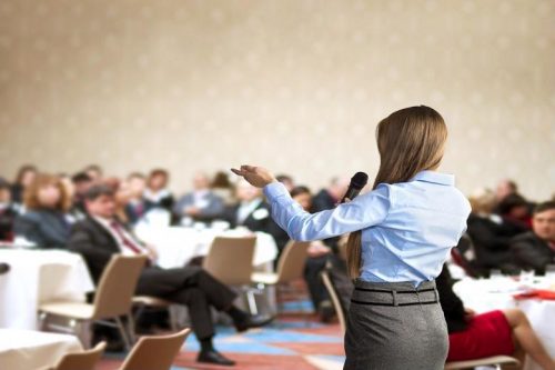 Businesswoman with microphone speaking at convention.
