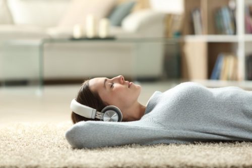 A social worker is relaxing at home while listening to music on headphones.
