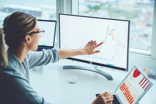 An accountant at work points to a graph on a screen.