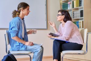 A social worker and their young client speak while seated across from each other.