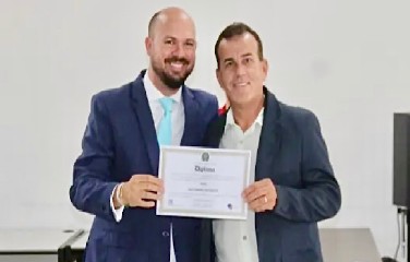 À direita, Guene recebe diploma das mãos do advogado Tiago Mascarenhas