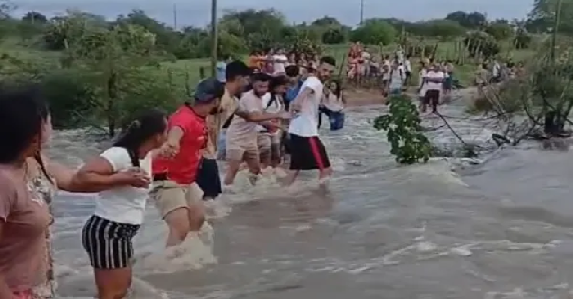 Ontem, moradores chegaram a formar um cordão humano para ajudar estudantes a atravessar uma estrada tomada pela correnteza
