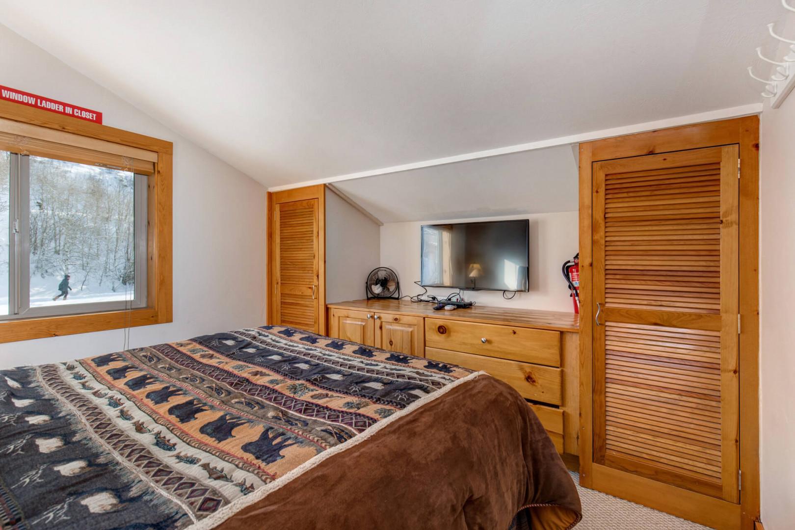 Cozy retreat with queen bed, TV, and ample storage space.