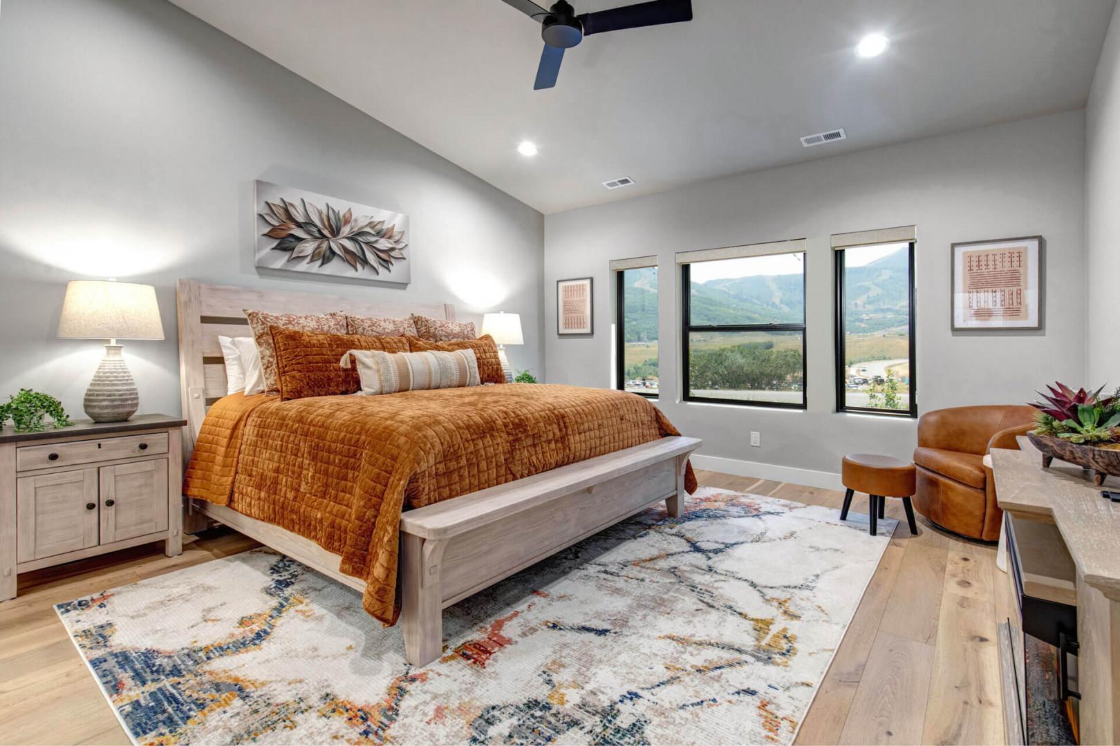 Wake up to sweeping mountain views through expansive windows that frame the natural beauty beyond. Your luxurious king bed, dressed in rich amber tones, invites you to unwind while savoring the peaceful landscape from the comfort of your retreat.