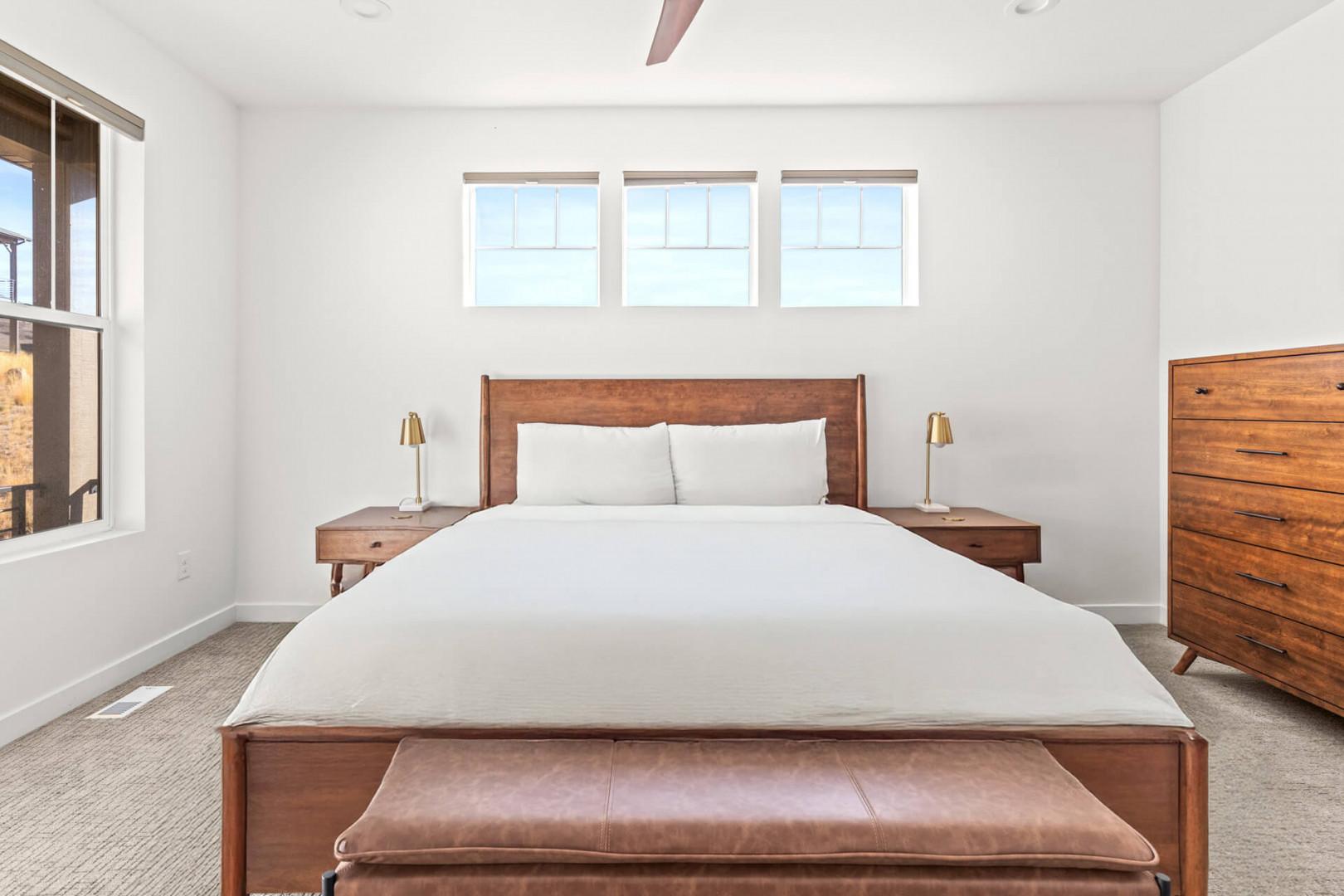 Sink into crisp white linens and wake to morning light streaming through transom windows. Your peaceful retreat features warm wood tones and sleek mid-century furnishings for effortless relaxation.
