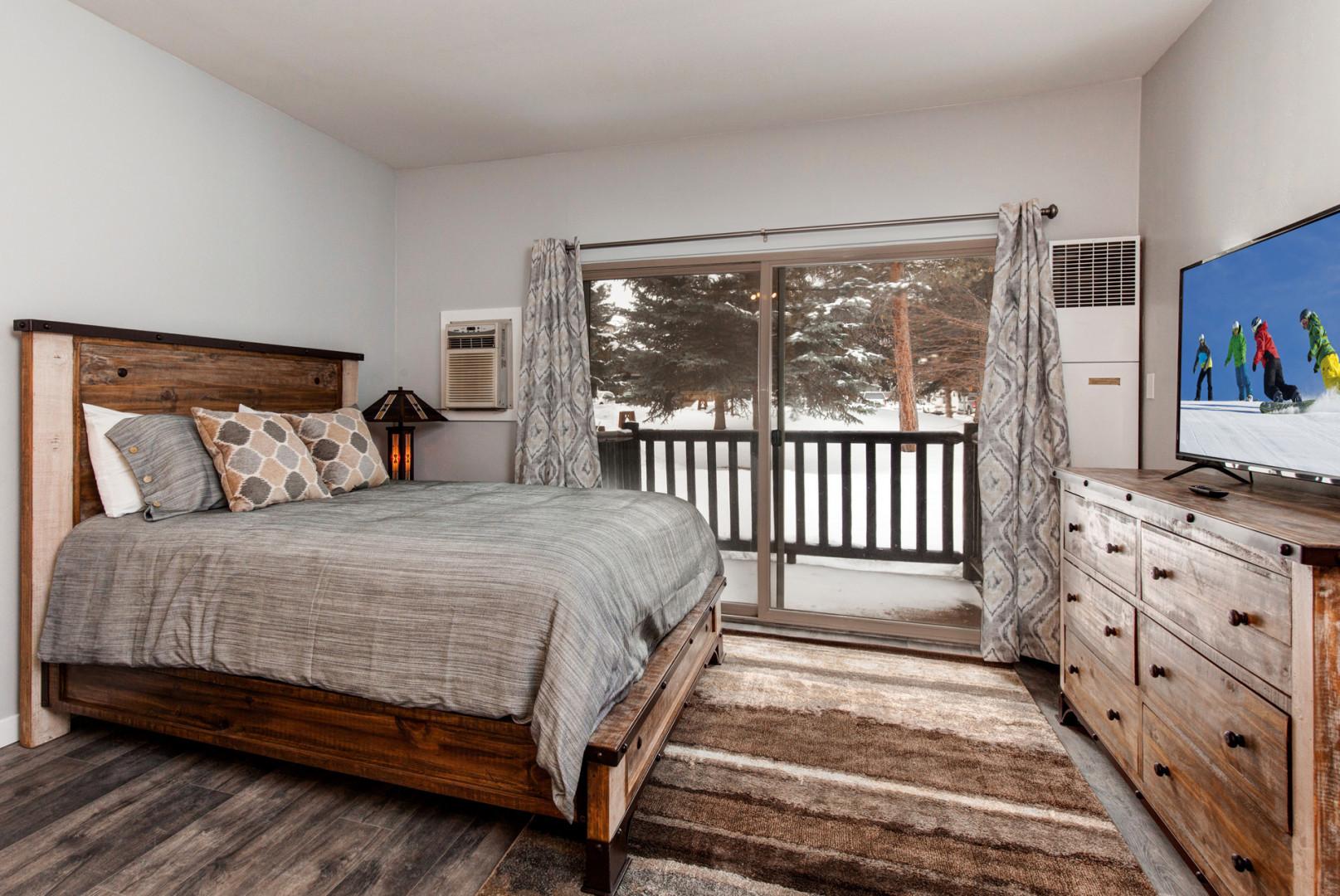 Serene queen bed next to charming outdoor patio, perfect for relaxation.