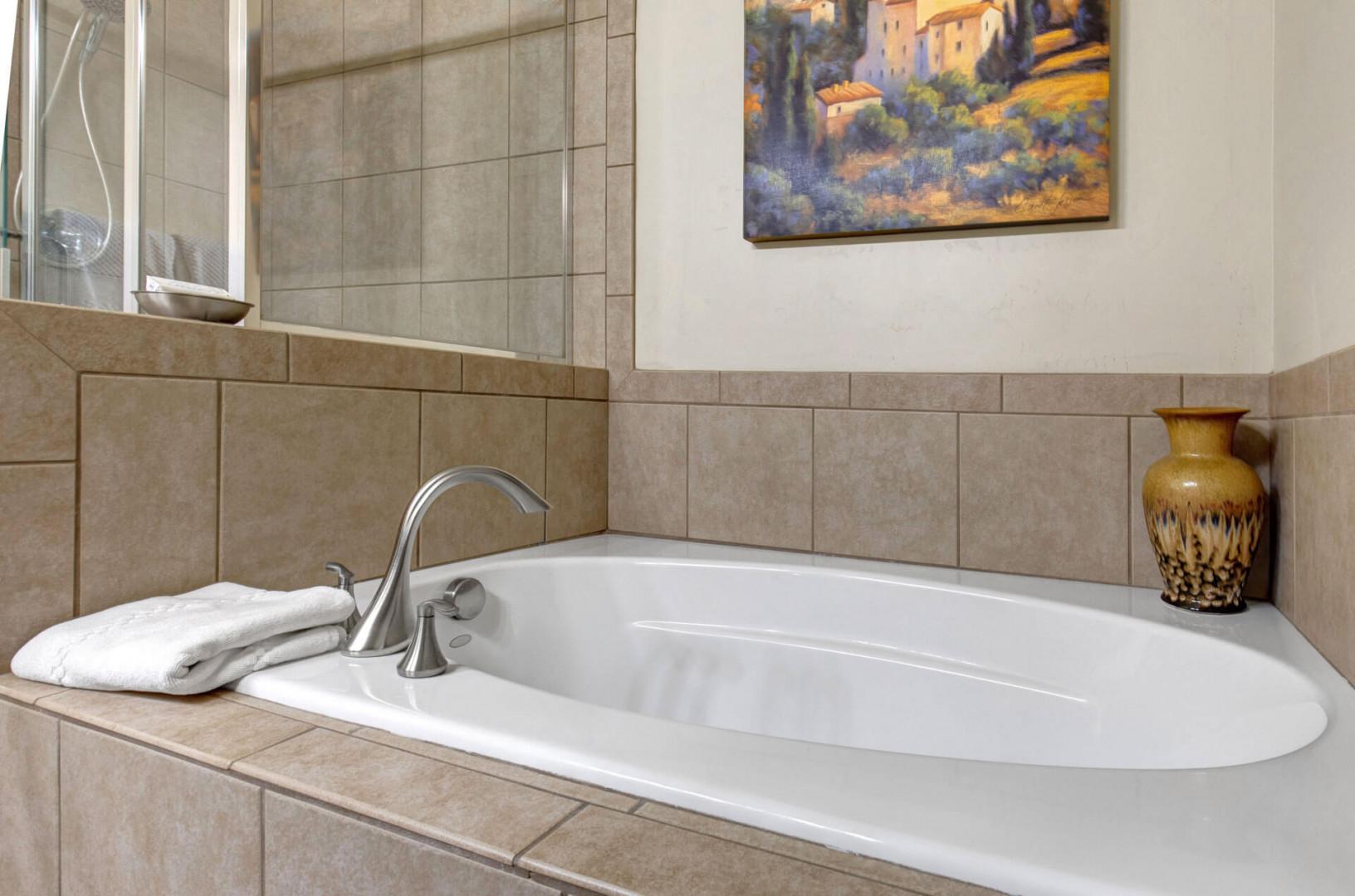 Sink into this elegant soaking tub where warm tile surrounds and artistic touches create your perfect retreat for unwinding after exploring.