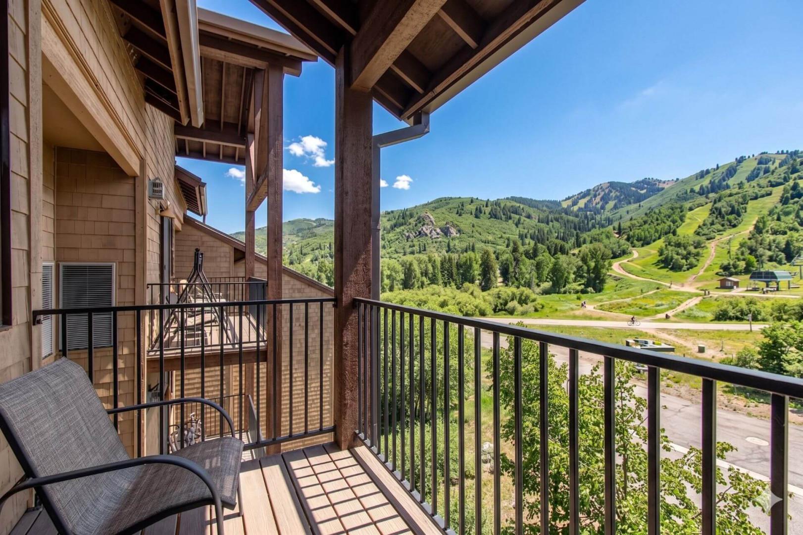A spacious private balcony frames sweeping mountain views, green slopes, and sunny blue skies—perfect for your morning coffee or quiet evening relaxation.
