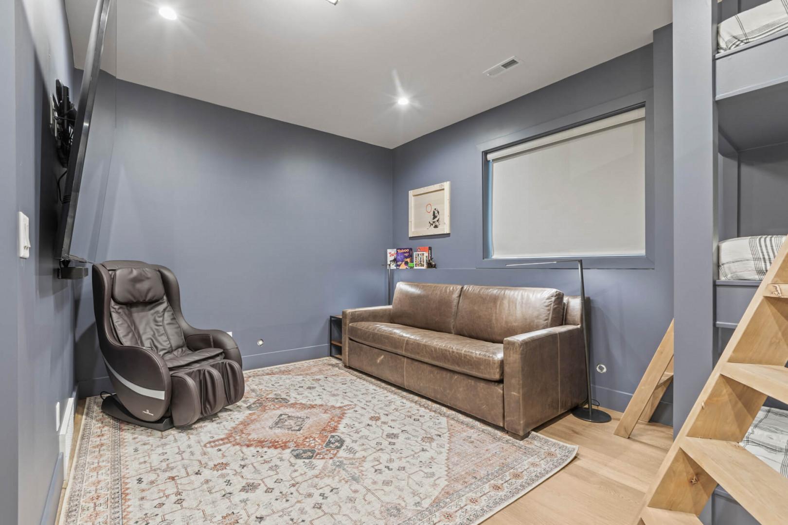 Cozy seating area with a massage chair and entertainment center.