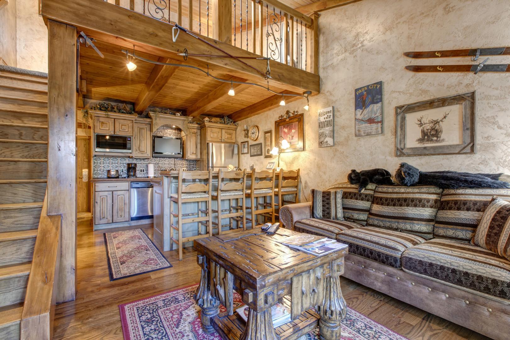 Cozy space with a sofa bed, center table, and bar stools by the kitchen bar table,