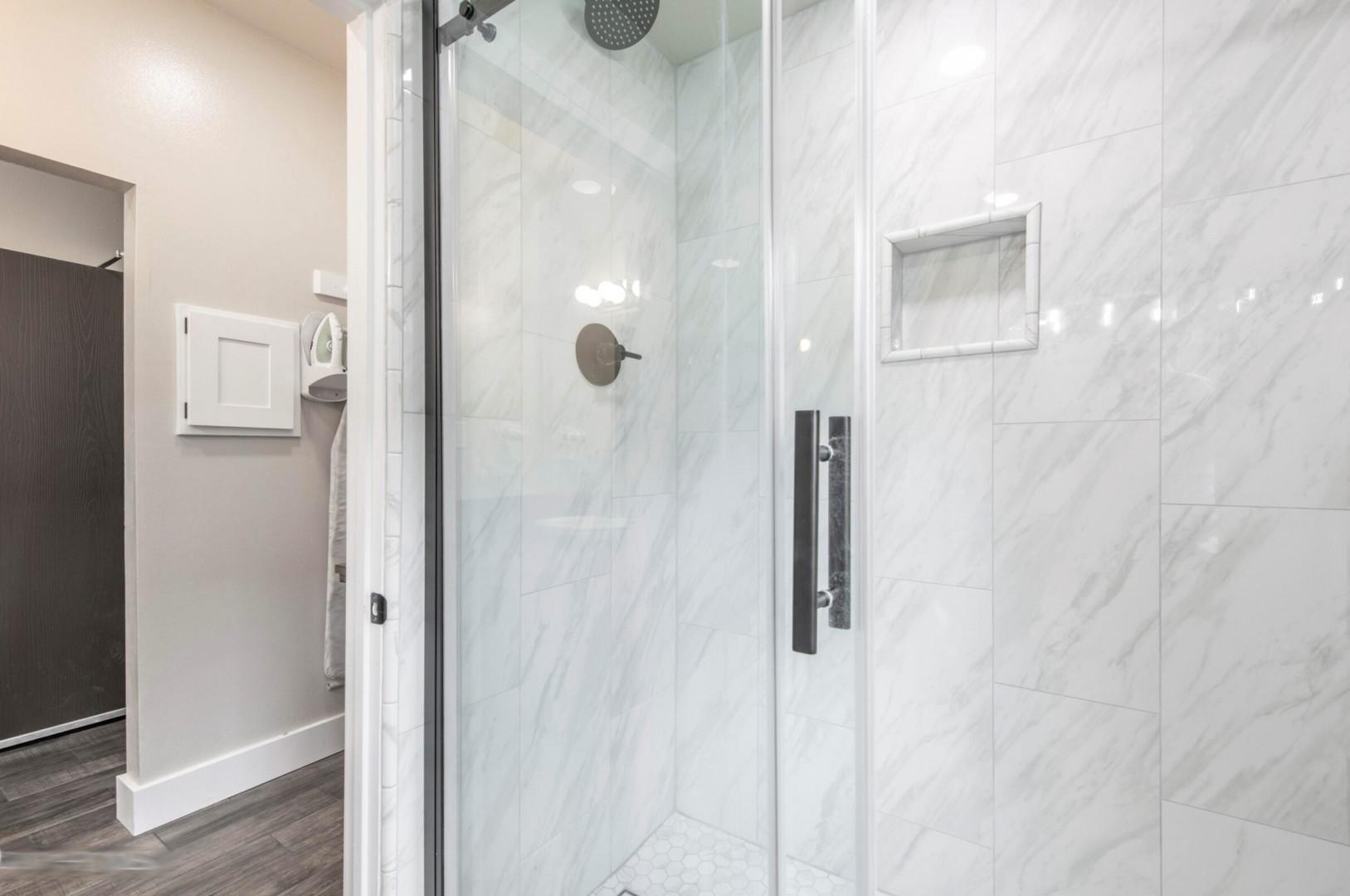 Sleek glass shower in a bright white tiled enclosure.