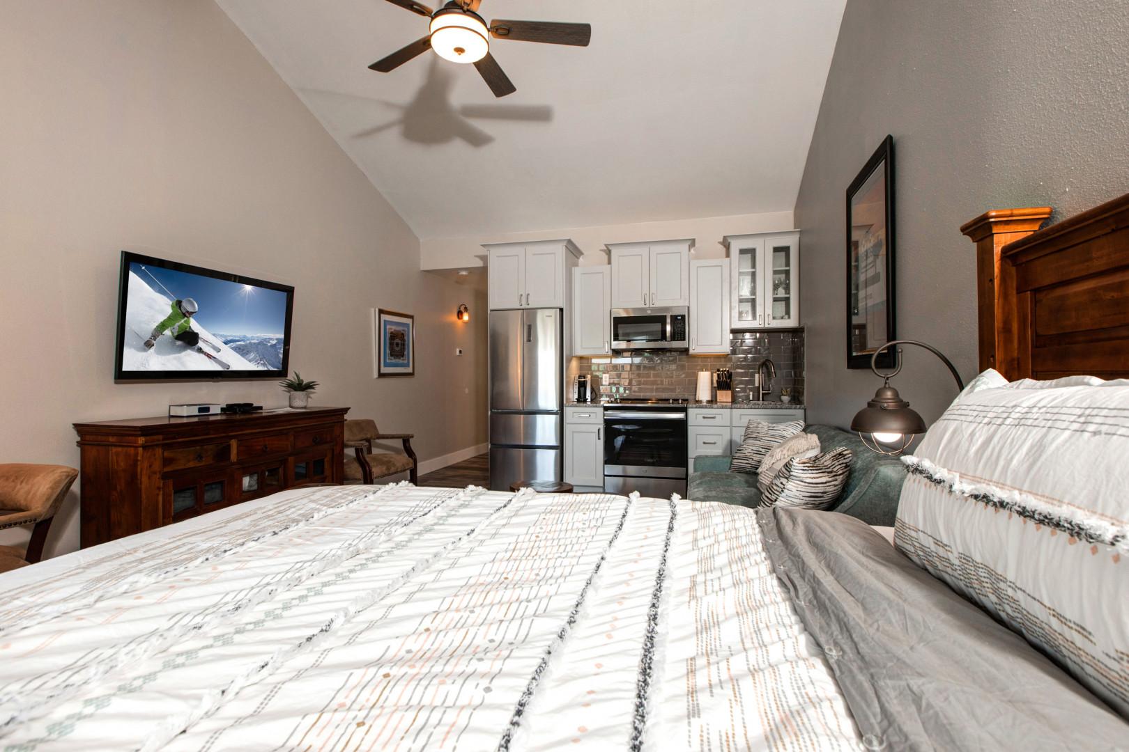 Cozy queen bed with a glimpse of the kitchen.