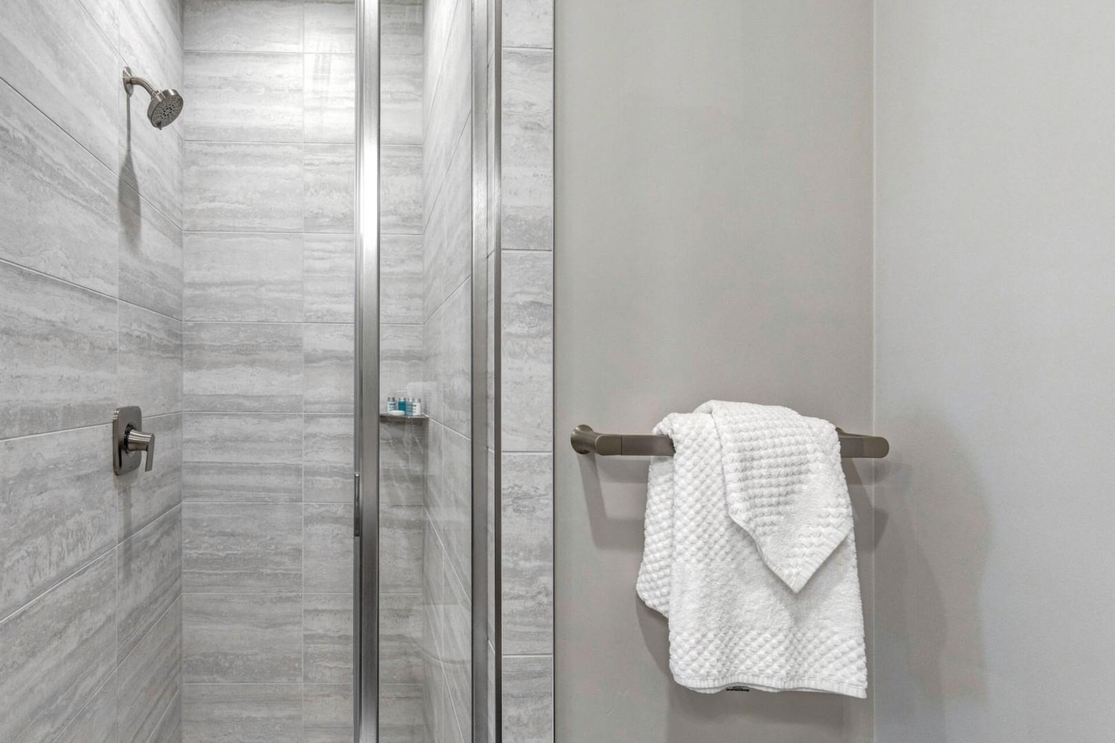 Refresh in your private walk-in shower, featuring stylish tile work and fresh towels ready for your use.
