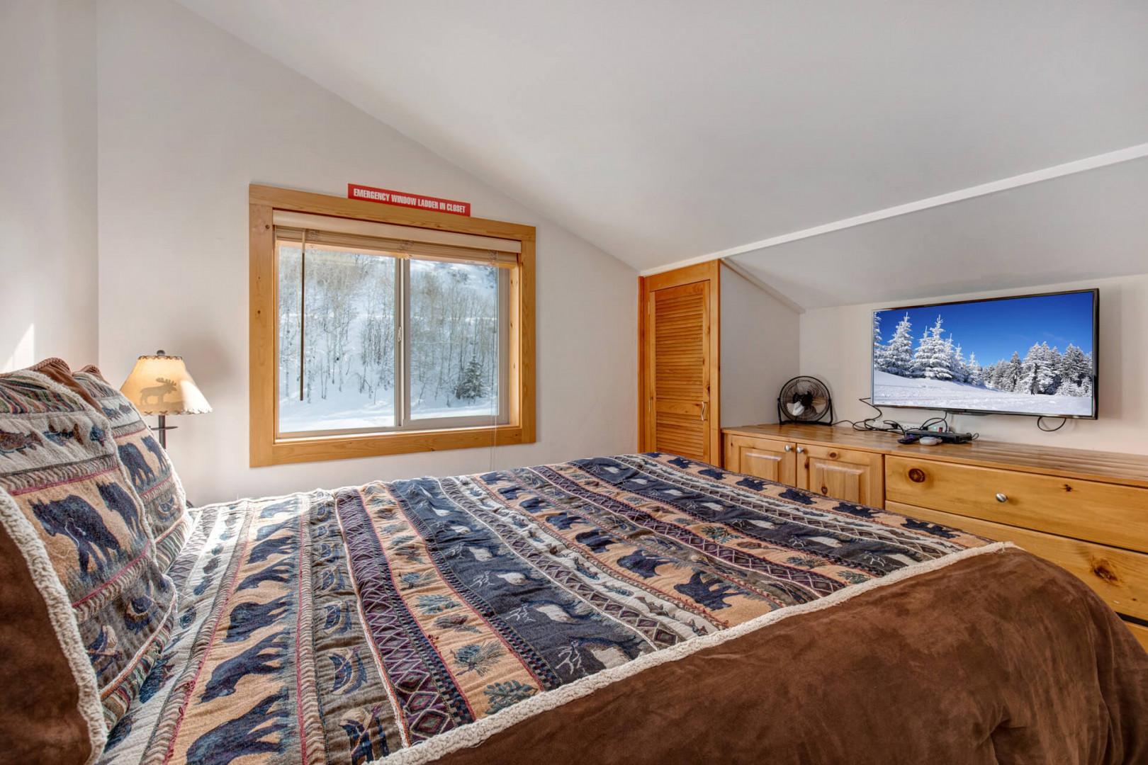 Cozy retreat with queen bed, TV, and ample storage space.