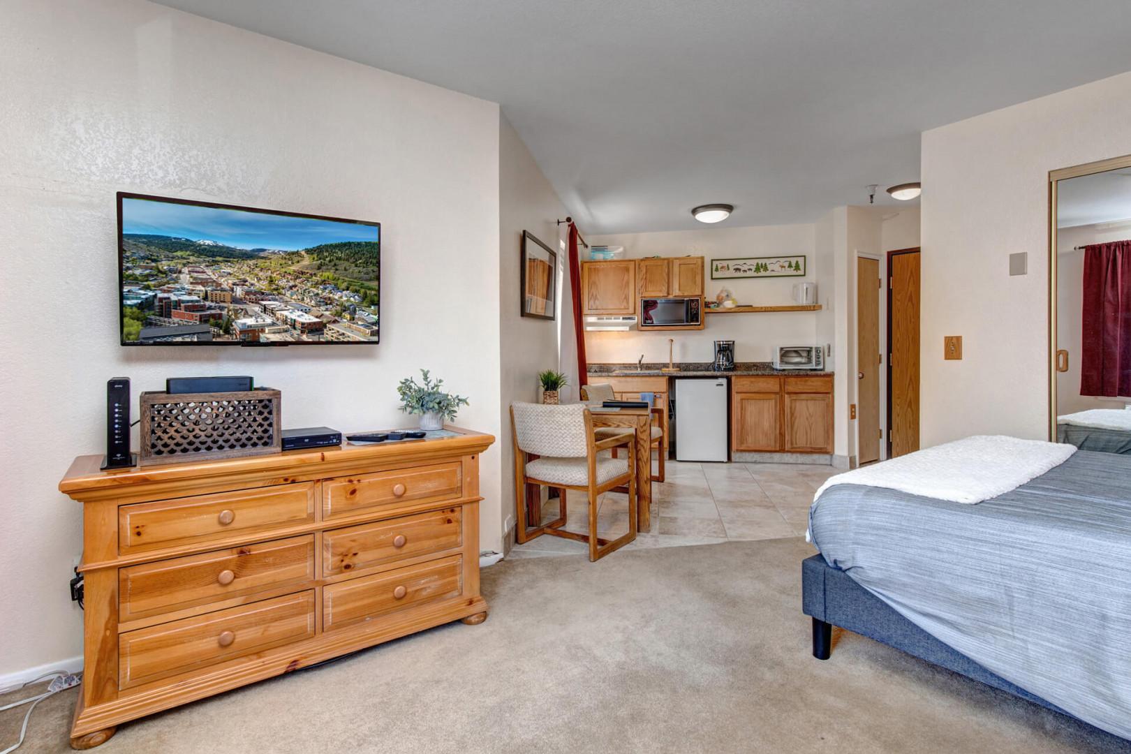 Cozy studio with queen bed, sofa, TV, and lovely window view.