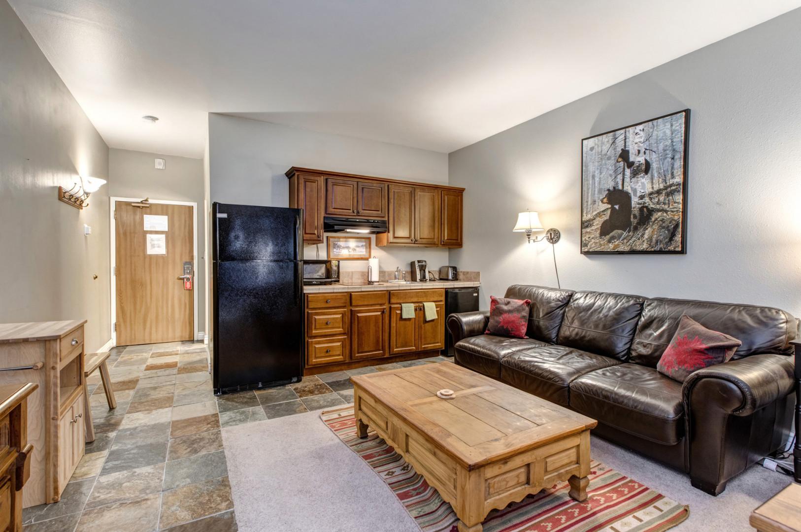 Cozy space with a sofa, center table, and kitchen view.