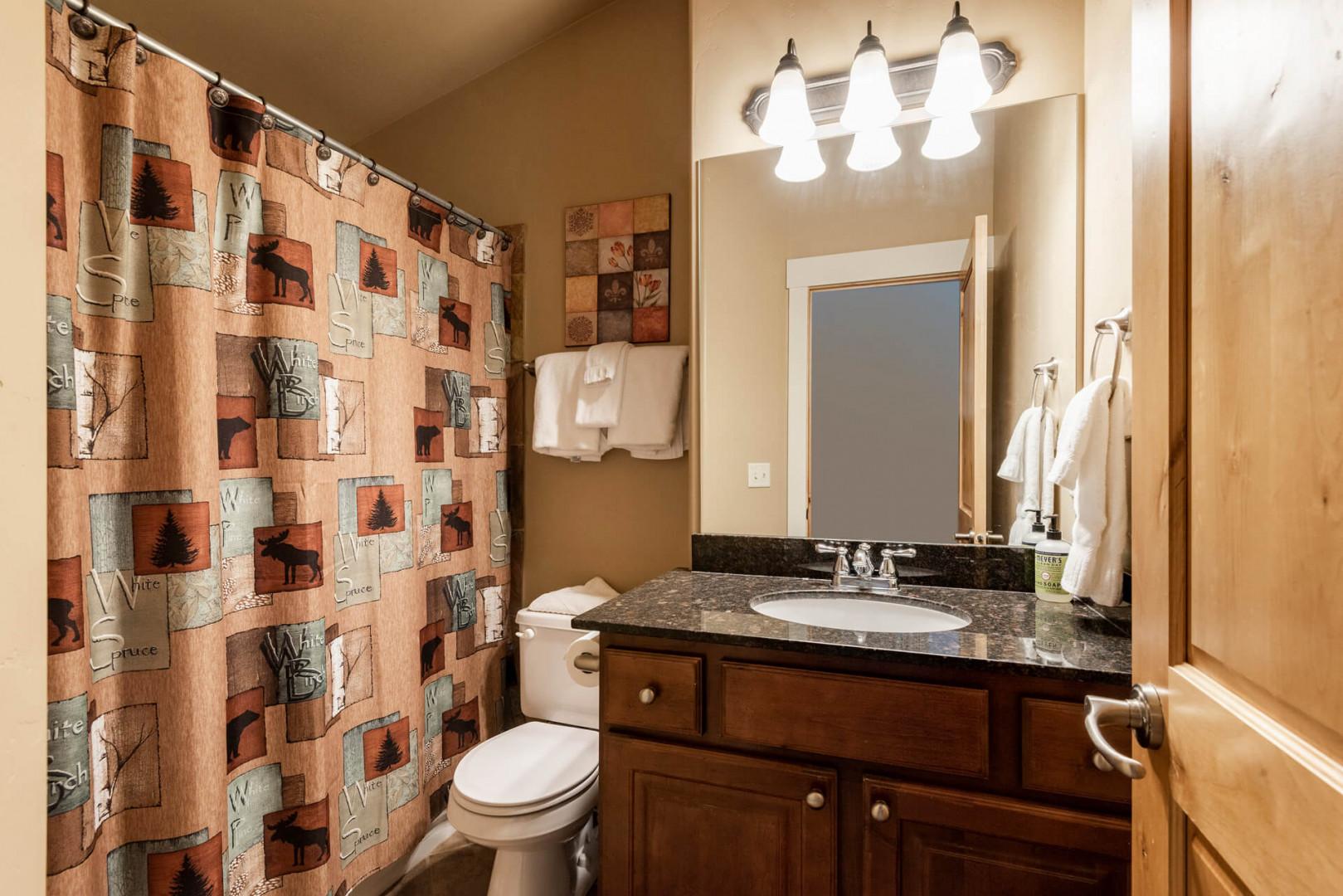 Bear Hollow 5557: Sleek sink, mirror, toilet, and shower in modern design.