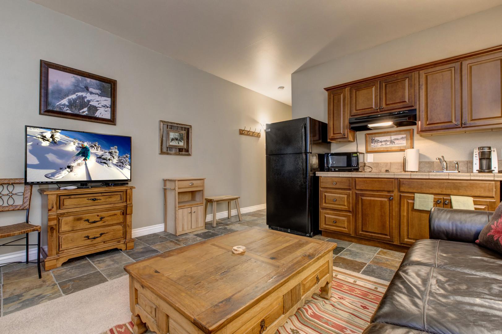 Cozy space with a sofa, center table, and kitchen view.