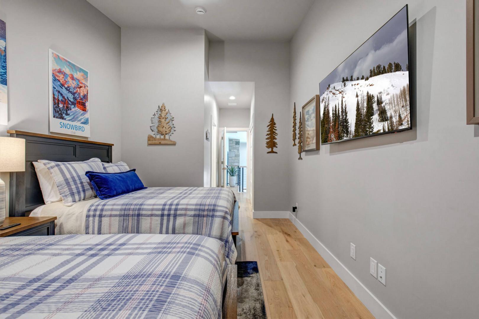 A cozy alpine-inspired bedroom awaits with warm wood accents, crisp blue-and-white plaid linens, and soft lighting—your perfect mountain retreat after a day on the slopes.