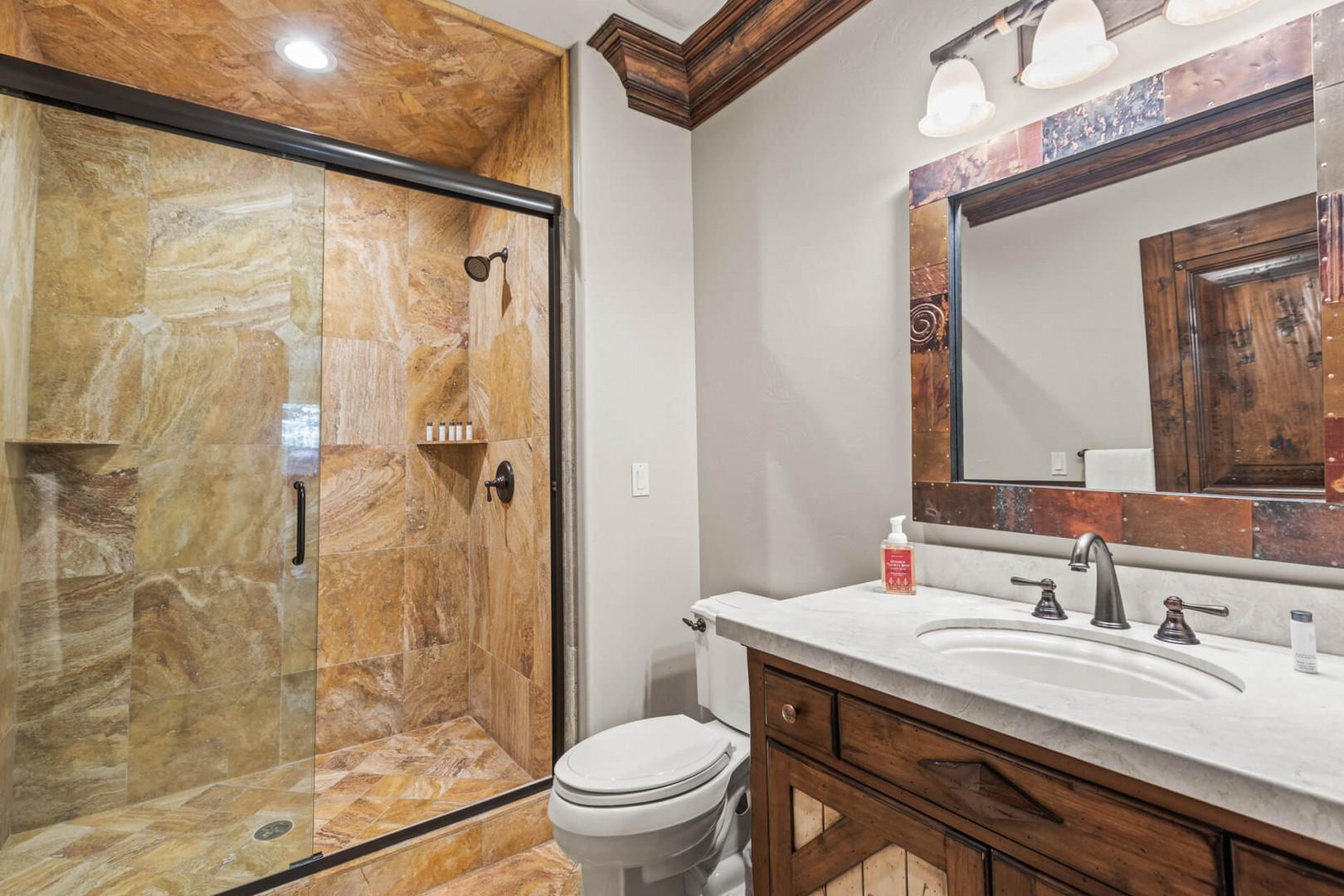 Sleek sink, mirror, toilet, and shower in modern design.