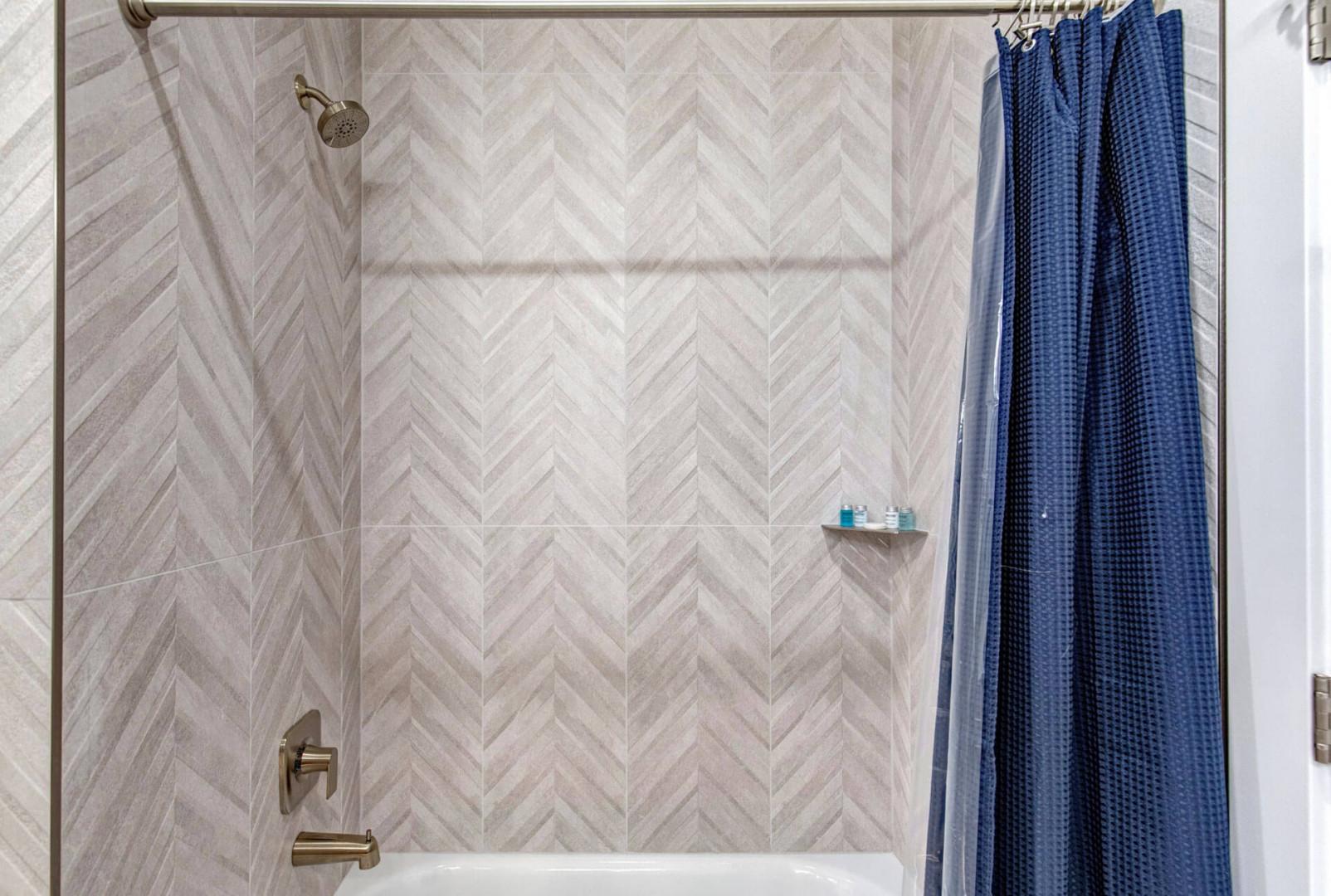 Step into your beautifully tiled bath with elegant herringbone walls and warm brass fixtures—your personal retreat awaits.