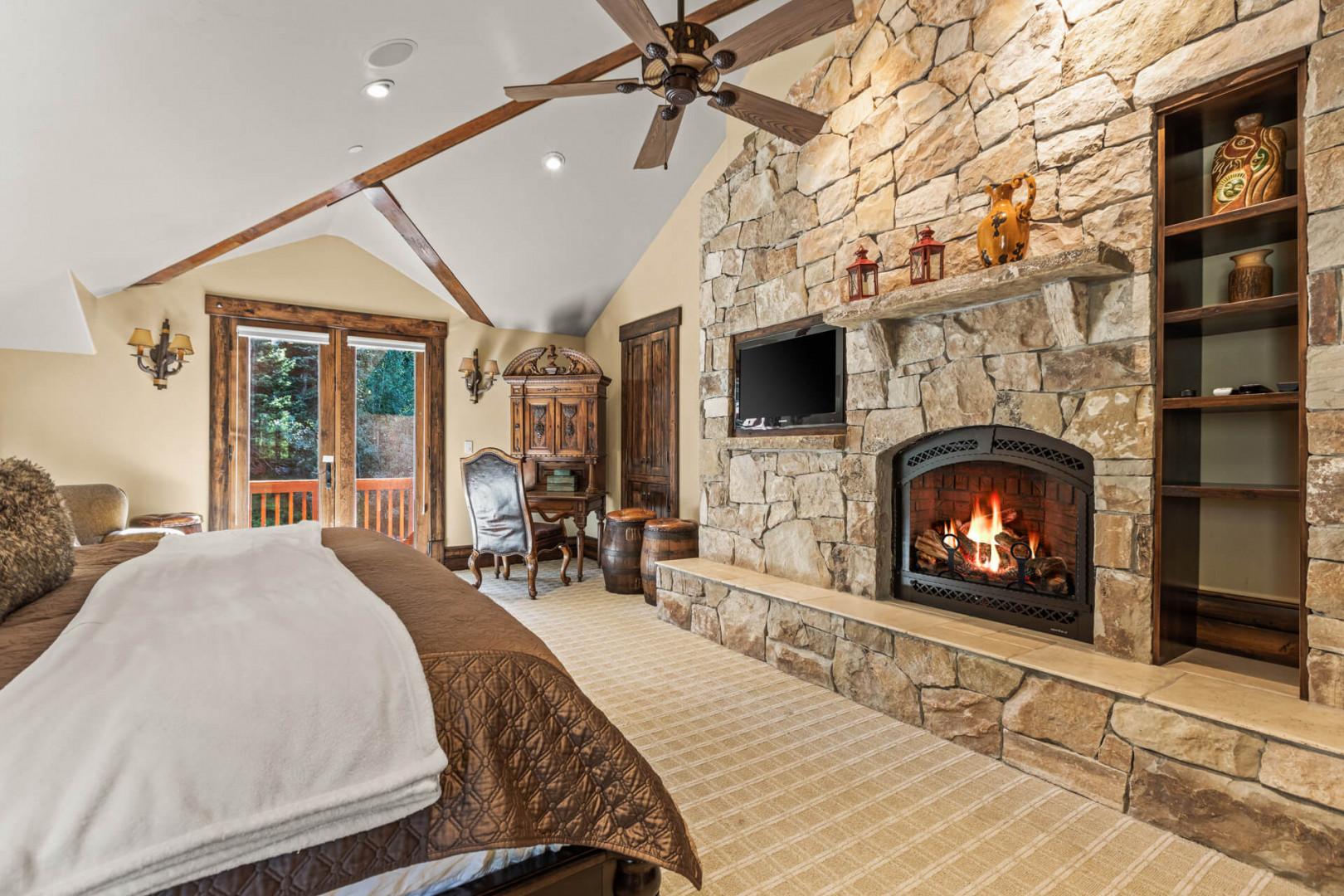 Luxurious king bed next to a stoned gas fireplace.