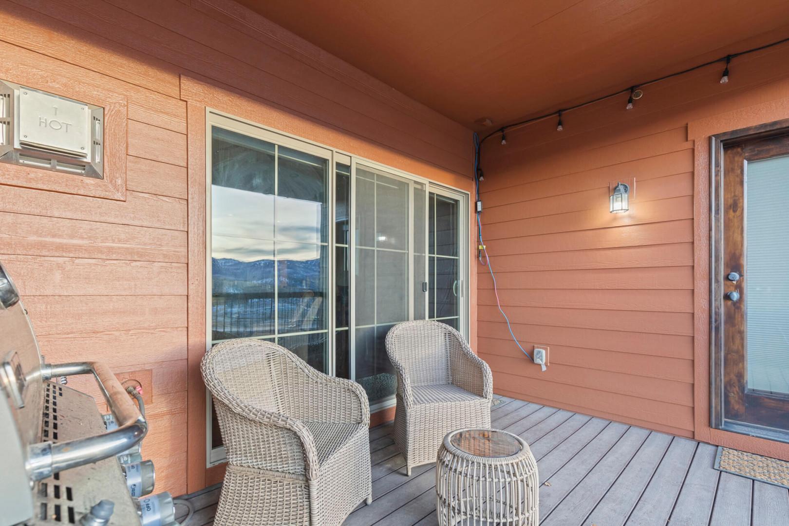 Relax in wicker chairs on your private covered patio, enjoying mountain views through expansive windows in this cozy wood-sided retreat.