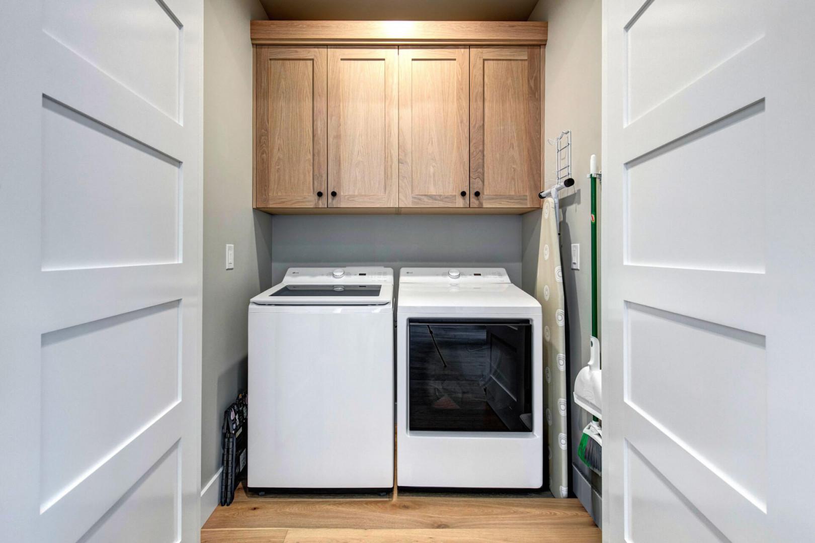 Your own dedicated laundry room keeps chores simple, with a full-sized washer and dryer tucked beneath warm oak cabinetry for extra linens and supplies.