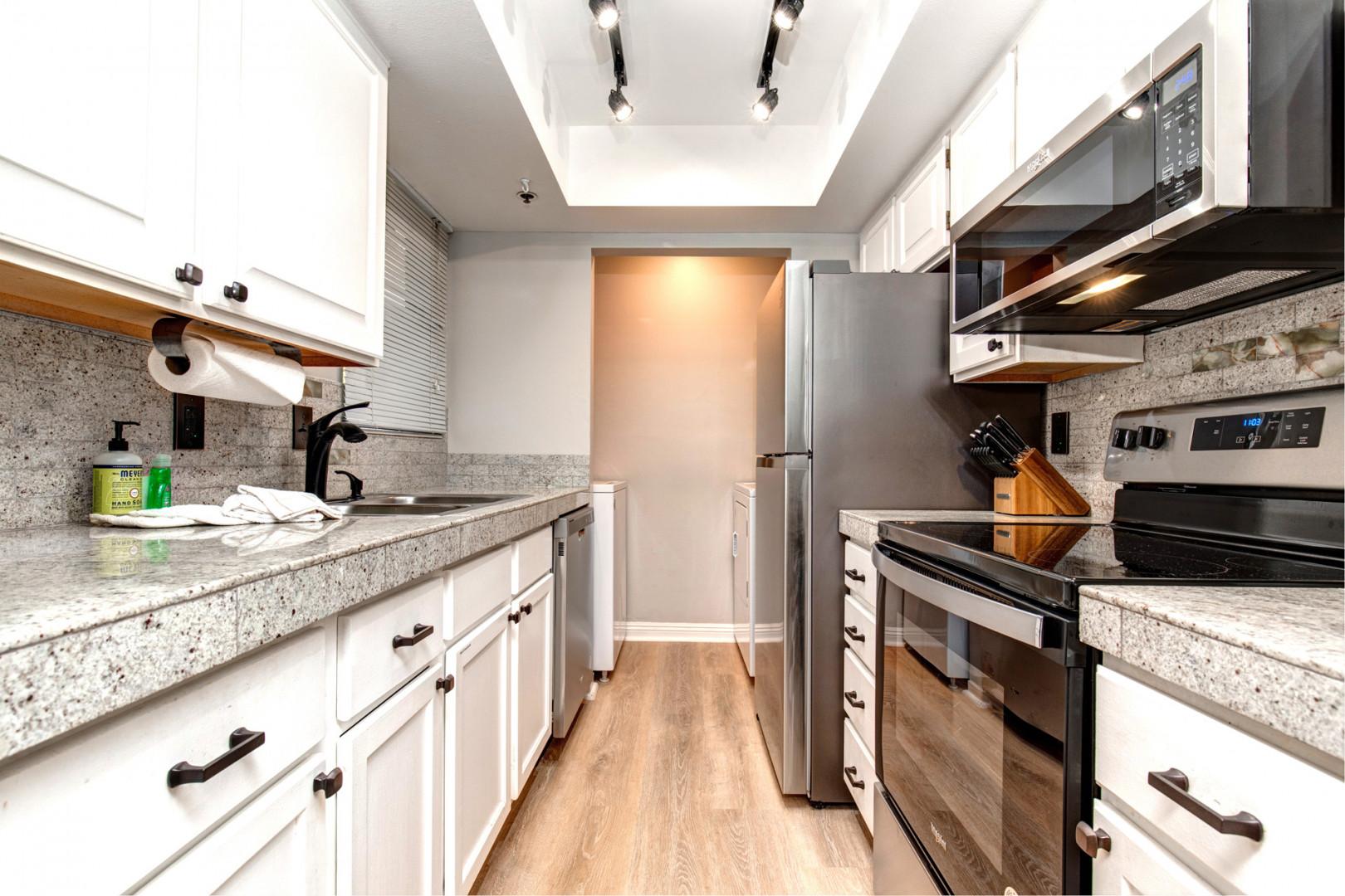 Powderwood 7B: Modern appliances and ample storage in sleek kitchen design.