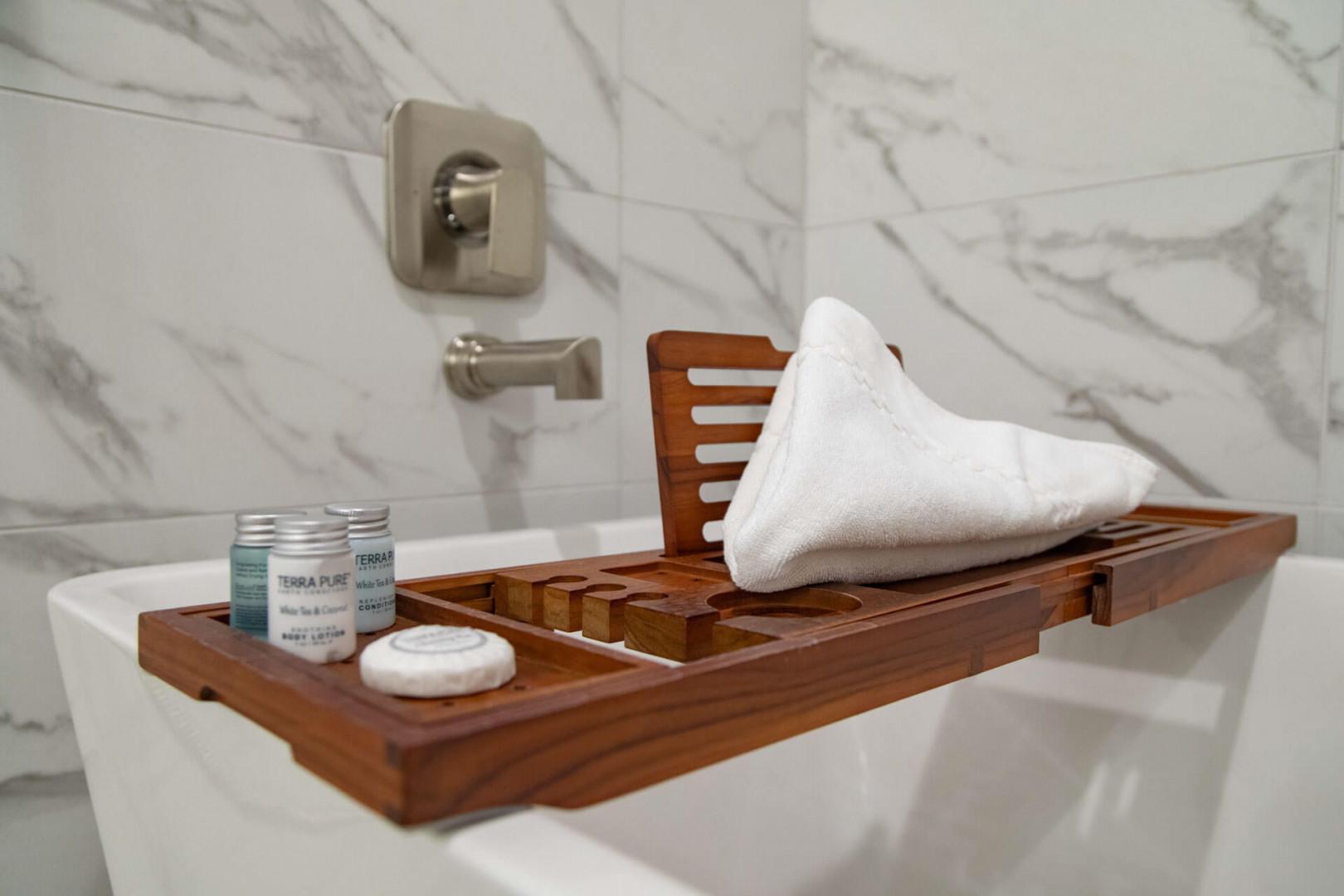 Relax in your spa-like tub with a wooden bath caddy holding plush towels and premium bath products. The elegant marble surround and modern fixtures create the perfect setting for unwinding after a day of adventure.