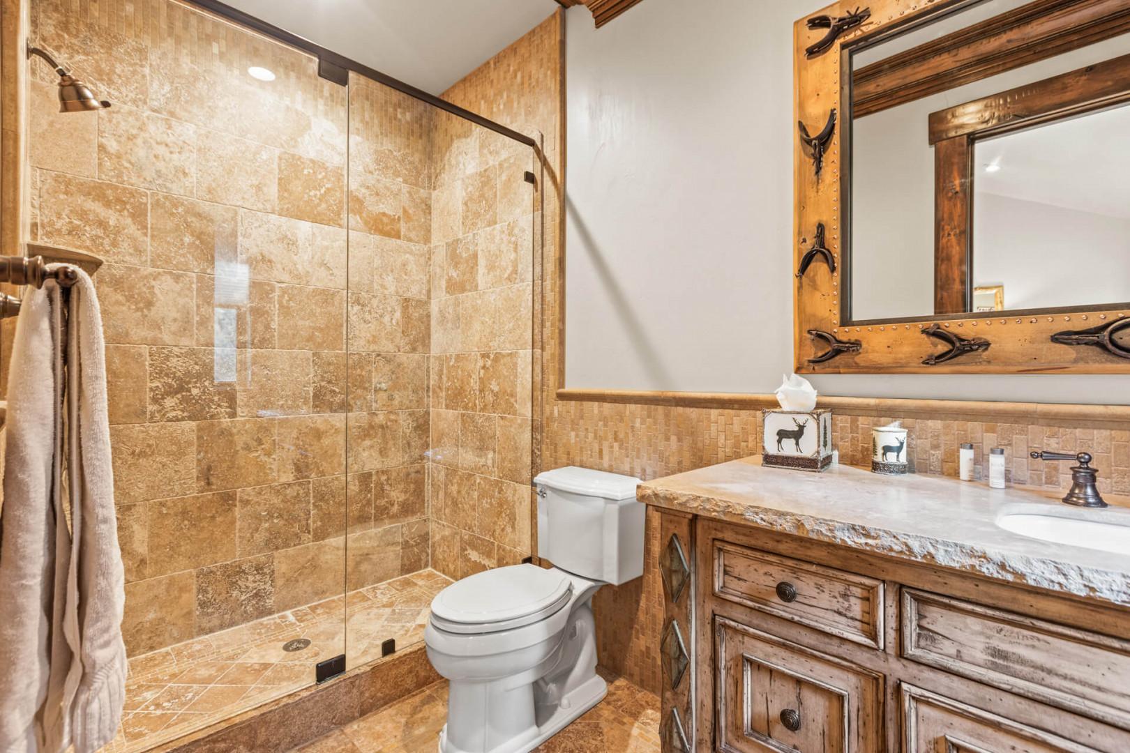 Sleek sink, mirror, toilet, and shower in modern design.