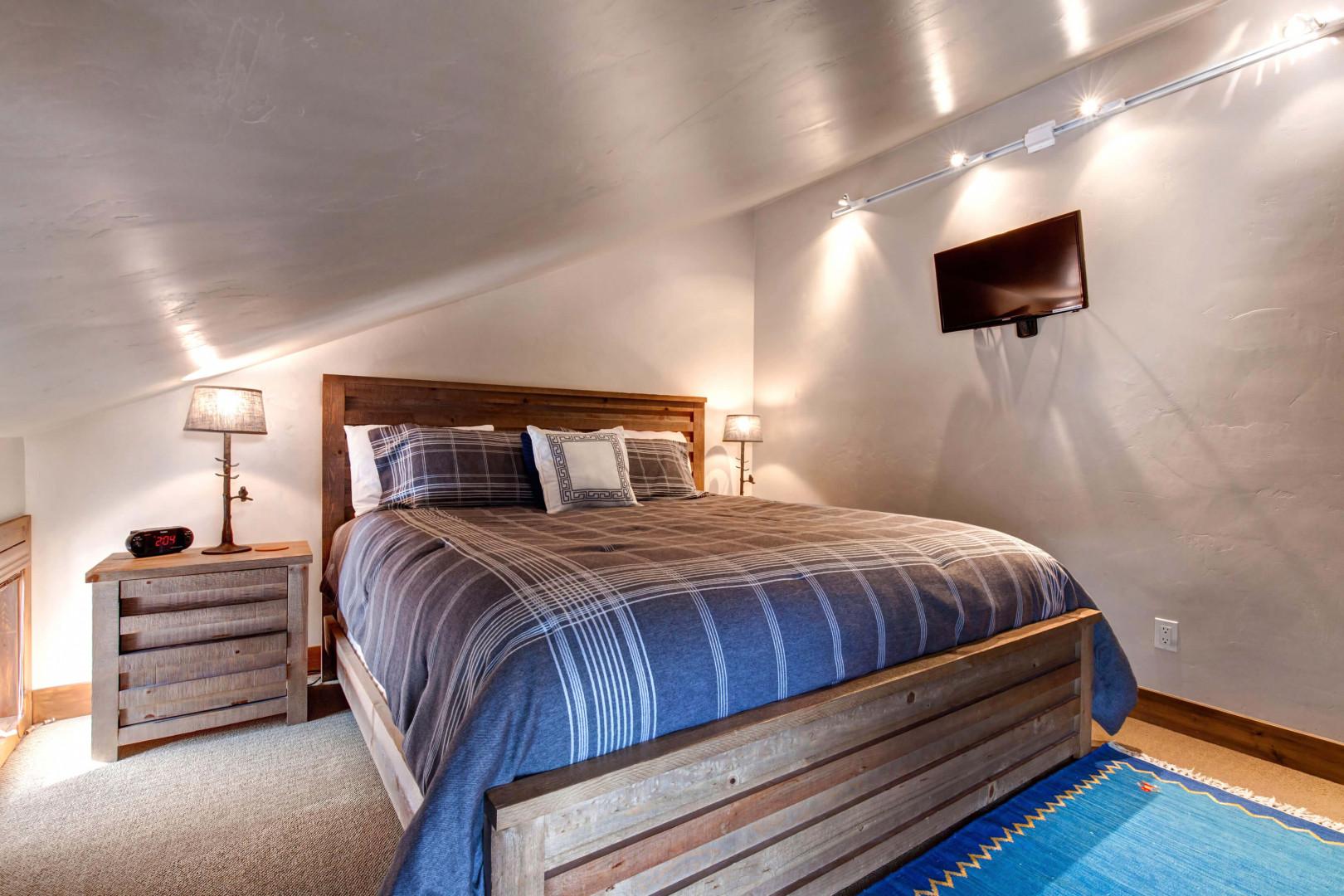 Cozy king bed flanked by stylish side tables and a window.