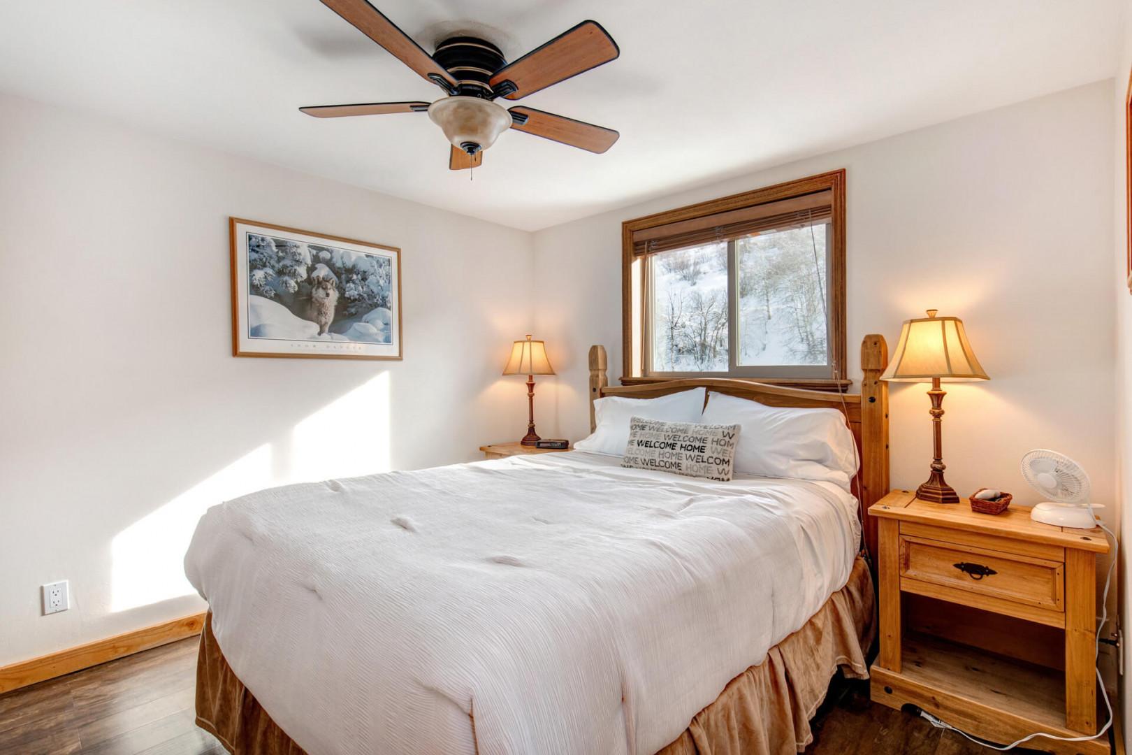 Cozy queen bed with a view, flanked by two lampshades.