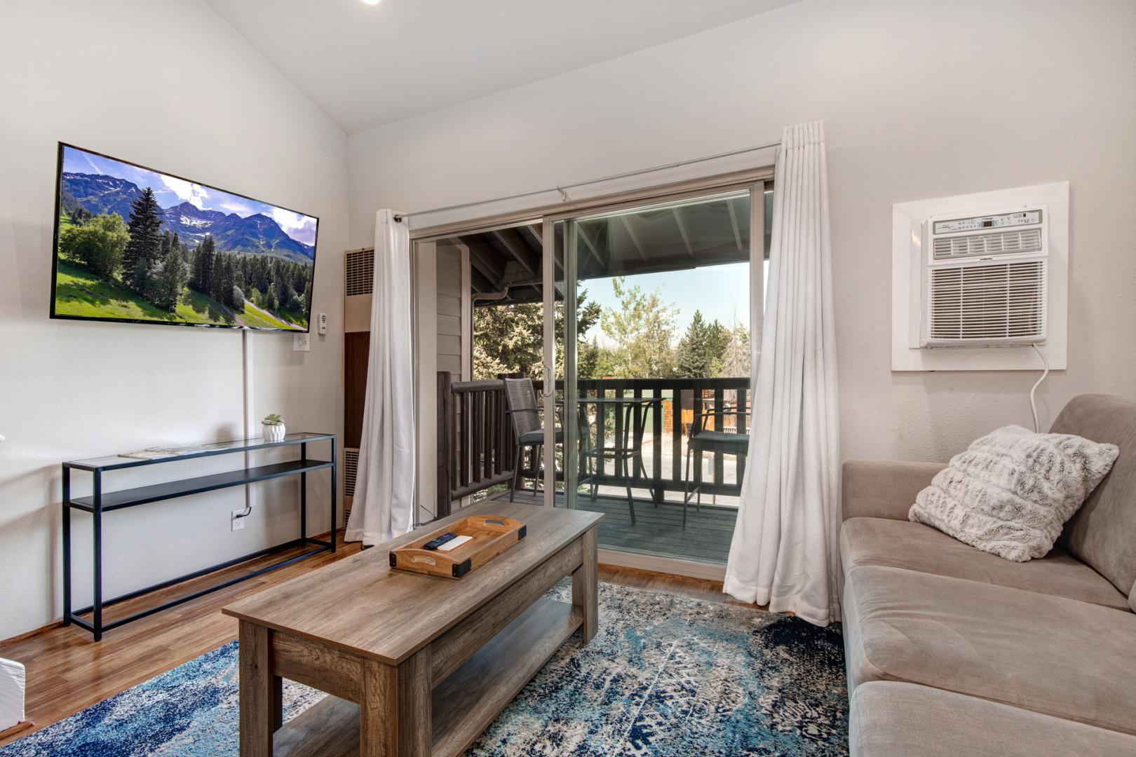 Cozy sofa bed, TV, and outdoor patio with chairs.