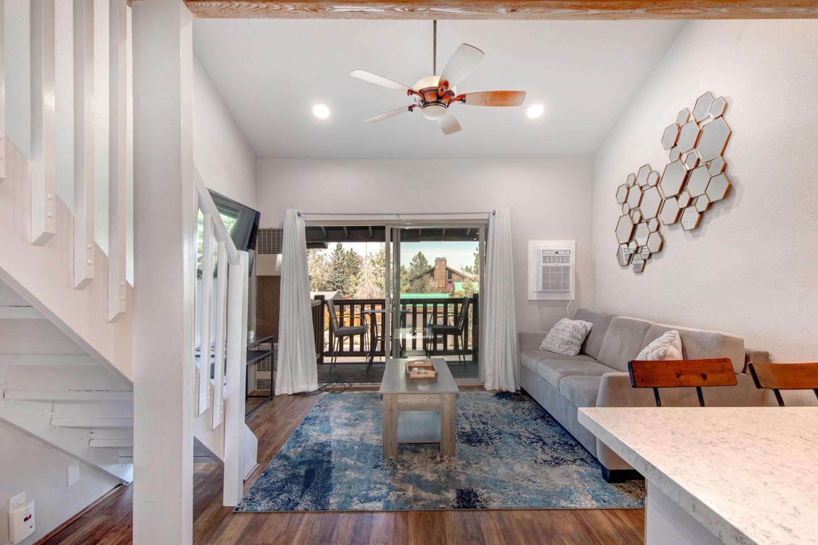 Cozy sofa bed, TV, and outdoor patio with ceiling fan.