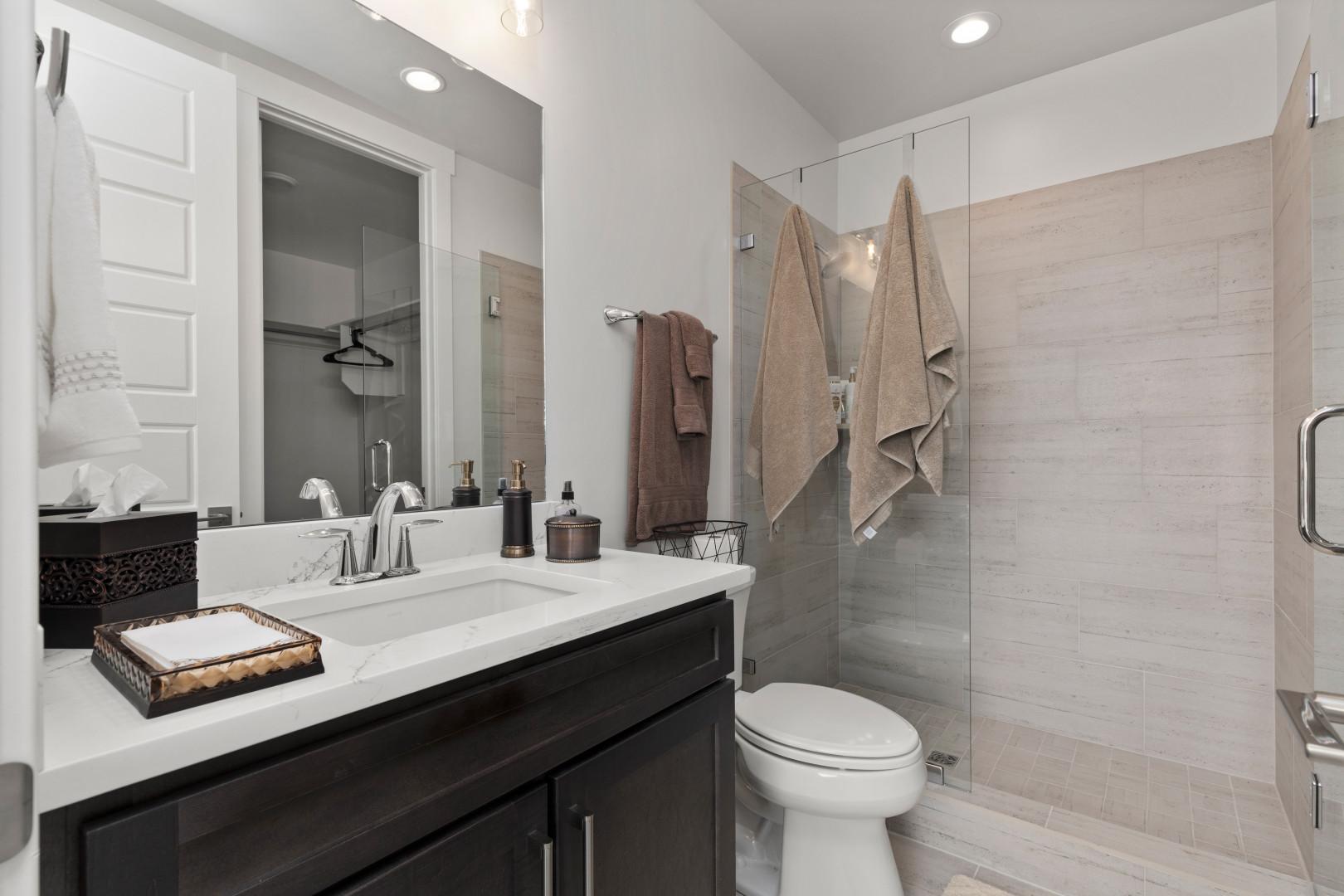 Deer Springs 12797: Sleek sink, mirror, toilet, and shower in modern design.