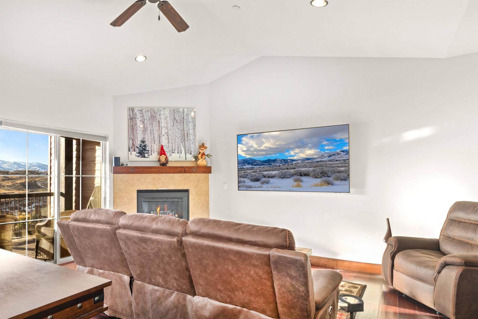 Relax in your spacious living room with plush leather seating, cozy fireplace, and stunning mountain views through floor-to-ceiling windows.