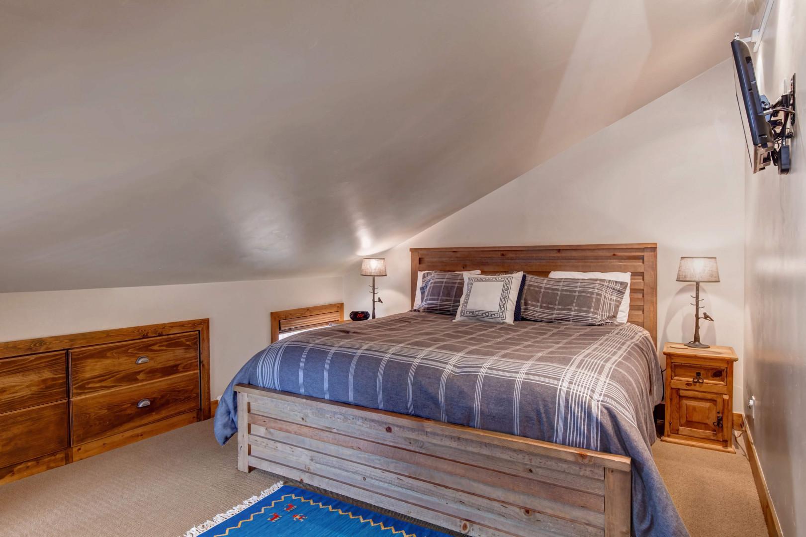 Cozy king bed flanked by stylish side tables and a window.