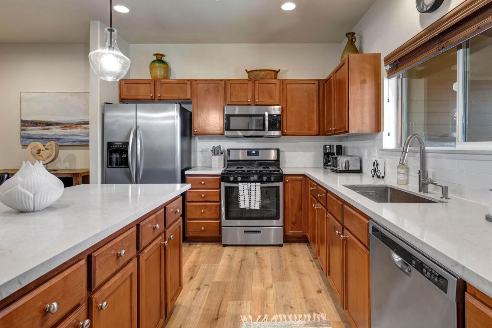 Your fully equipped kitchen awaits with stainless steel appliances, granite counters, and warm wood cabinetry.