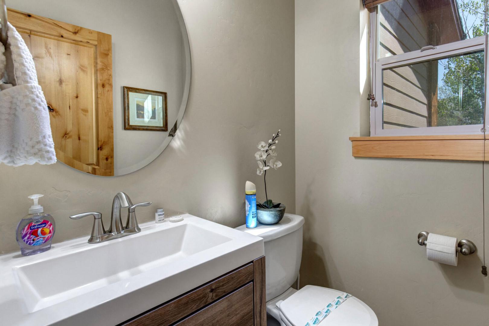 Step into your bright, modern main floor half bathroom featuring wood accents and natural light streaming through the window for your refreshing morning routine.
