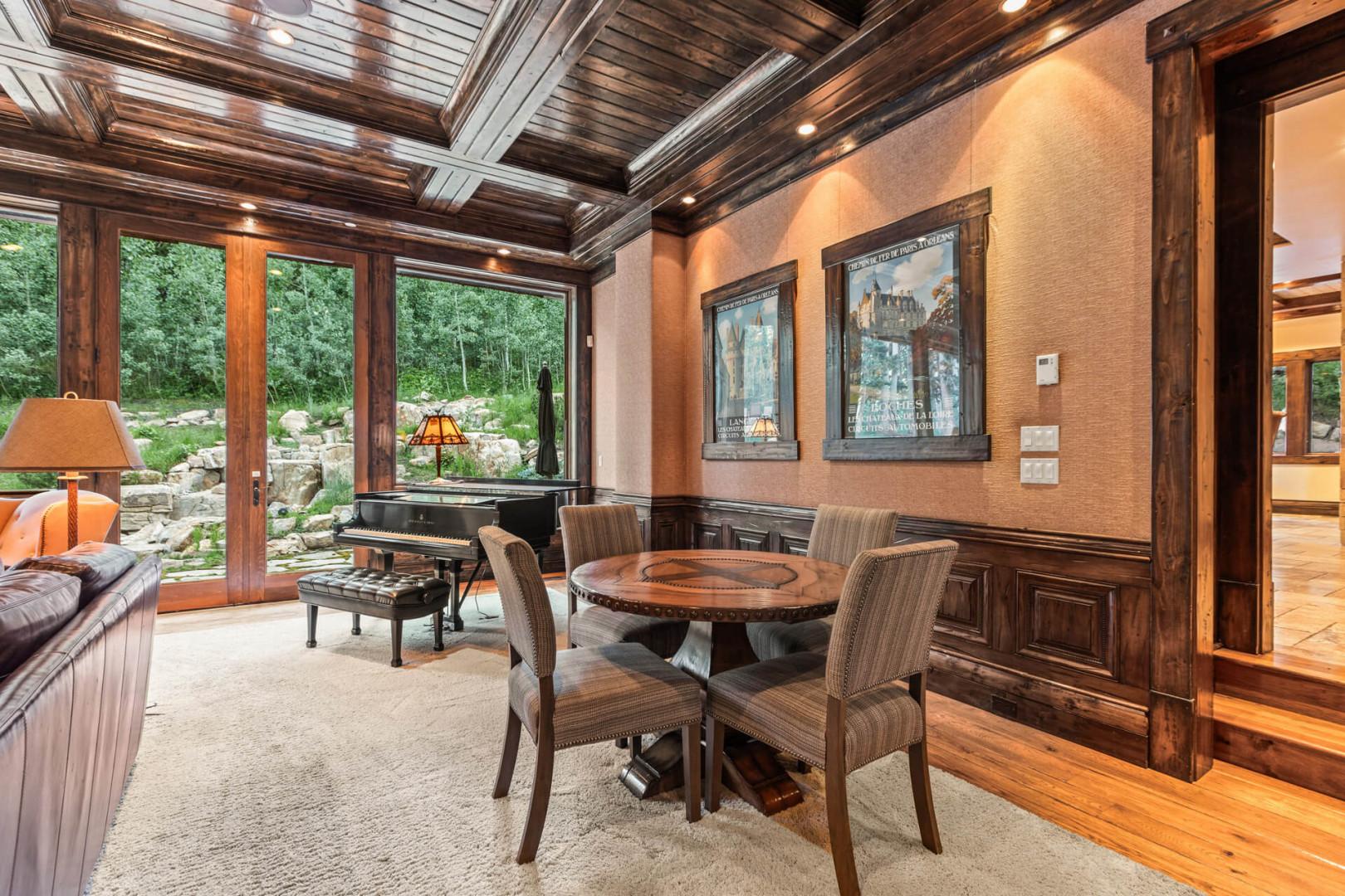 Piano, table, chairs, glass door to outdoor patio. Cozy vibes.