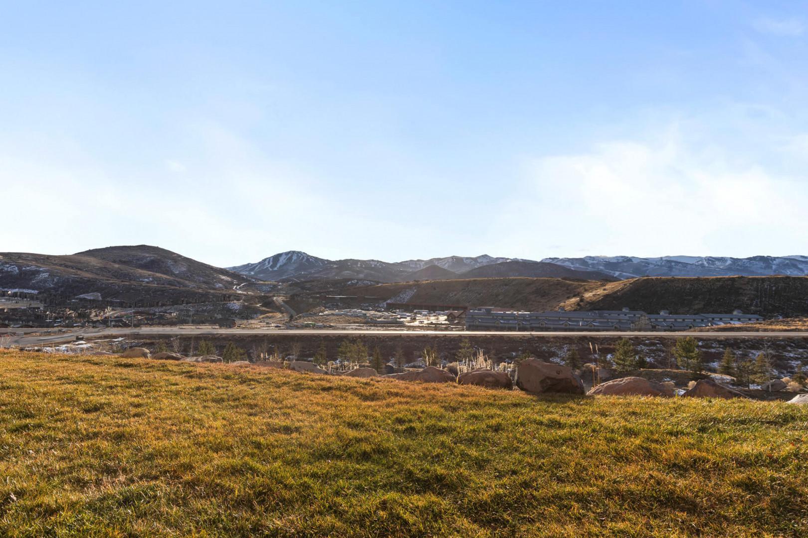 Expansive natural landscape with rolling hills and distant mountains under clear blue skies.